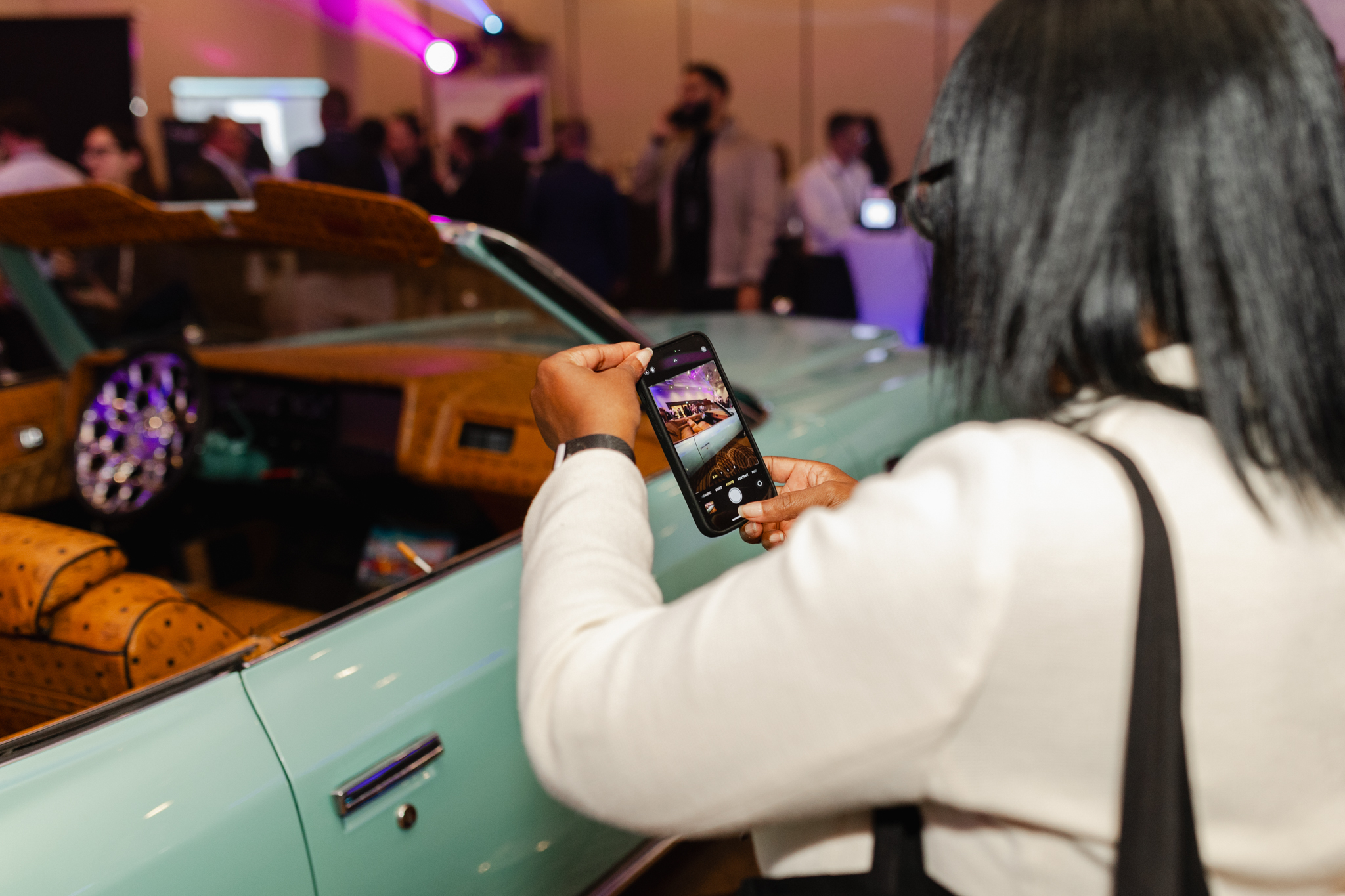 An event photographer capturing a woman photographing a car at an event.