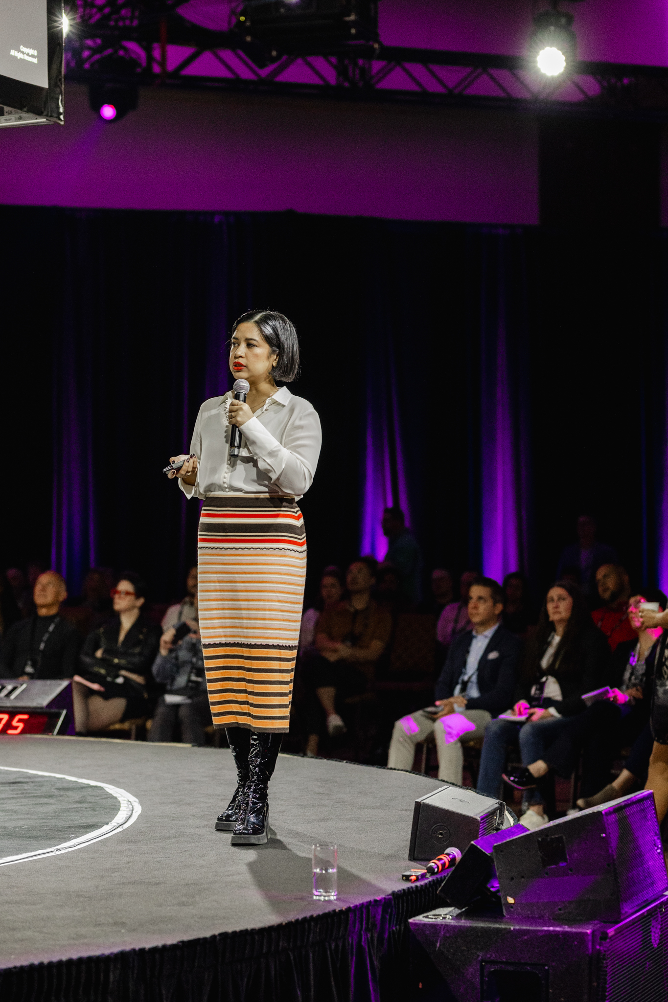 A woman delivering a speech on stage at an event, captured by event photography.