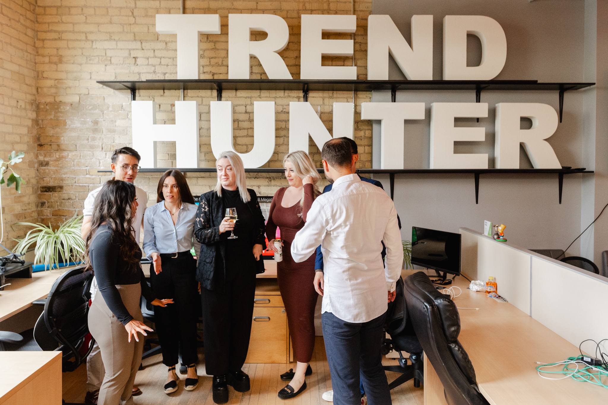 An event photographer capturing a group of people standing in front of a trend hunter sign.
