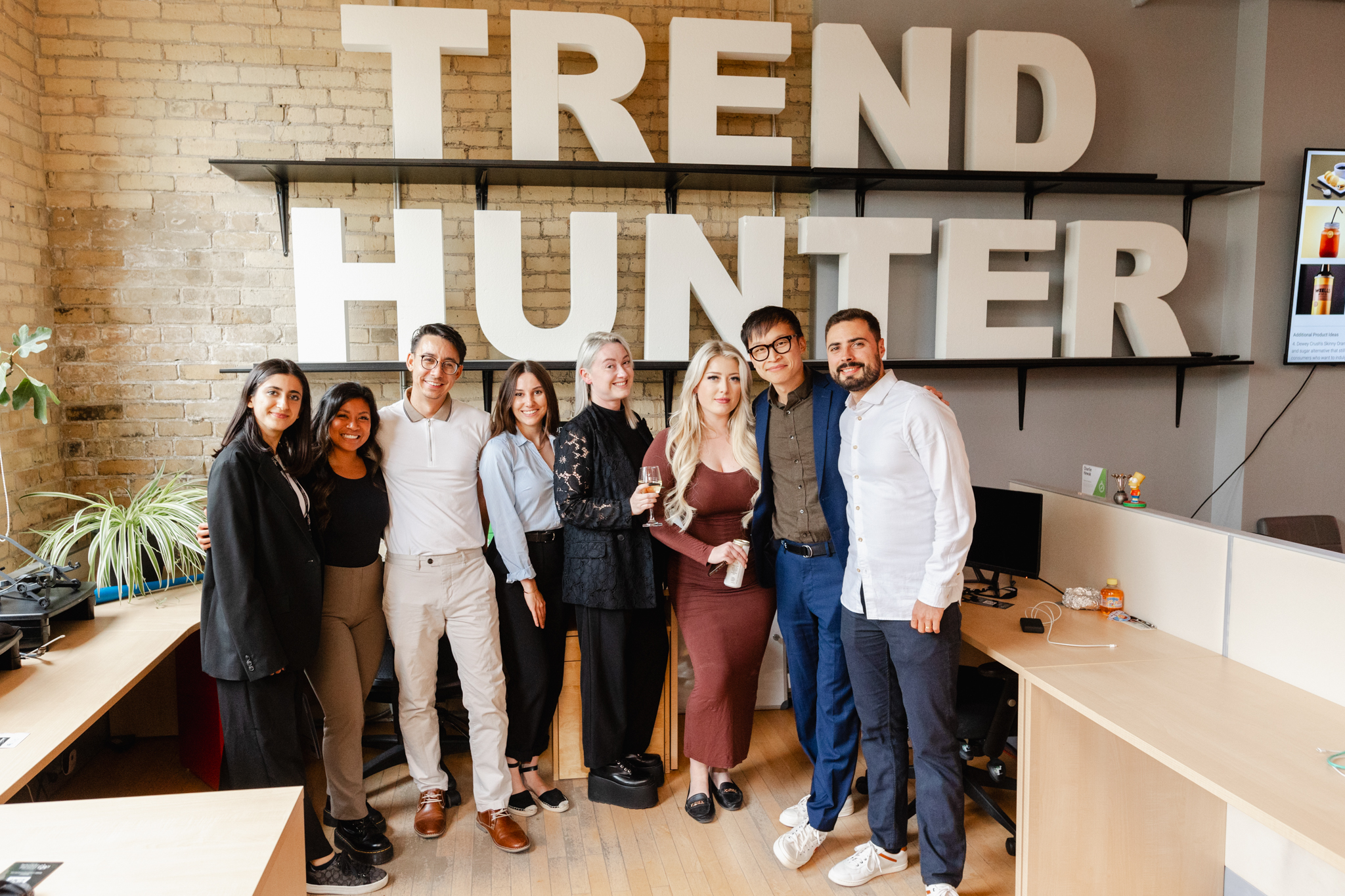 A group of people posing in front of a trend hunter sign captured by event photography.