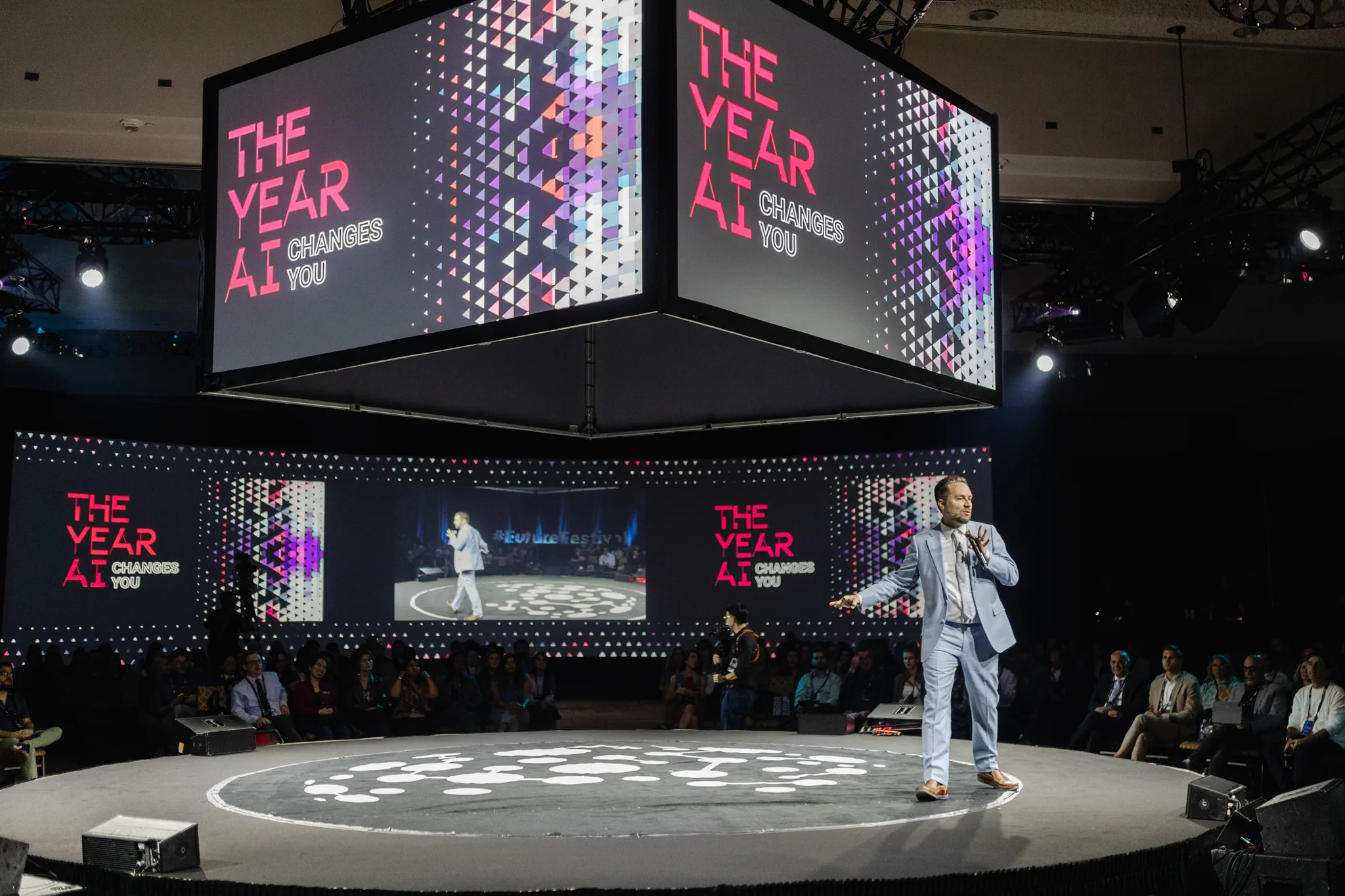 A man on stage during an event photography session, with a large screen as the backdrop.