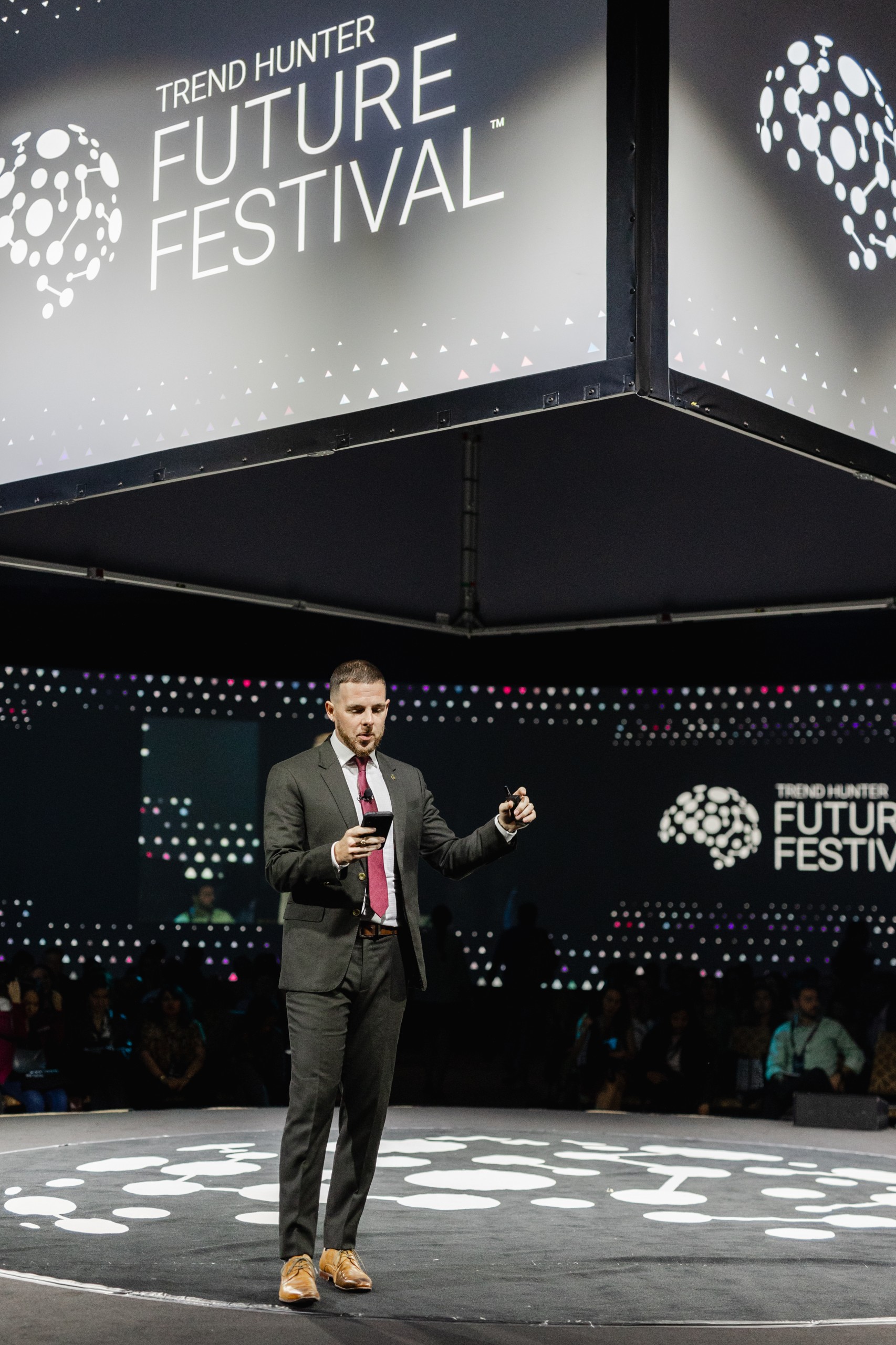 An elegantly dressed man standing on stage at the future festival, captured in captivating event photography.