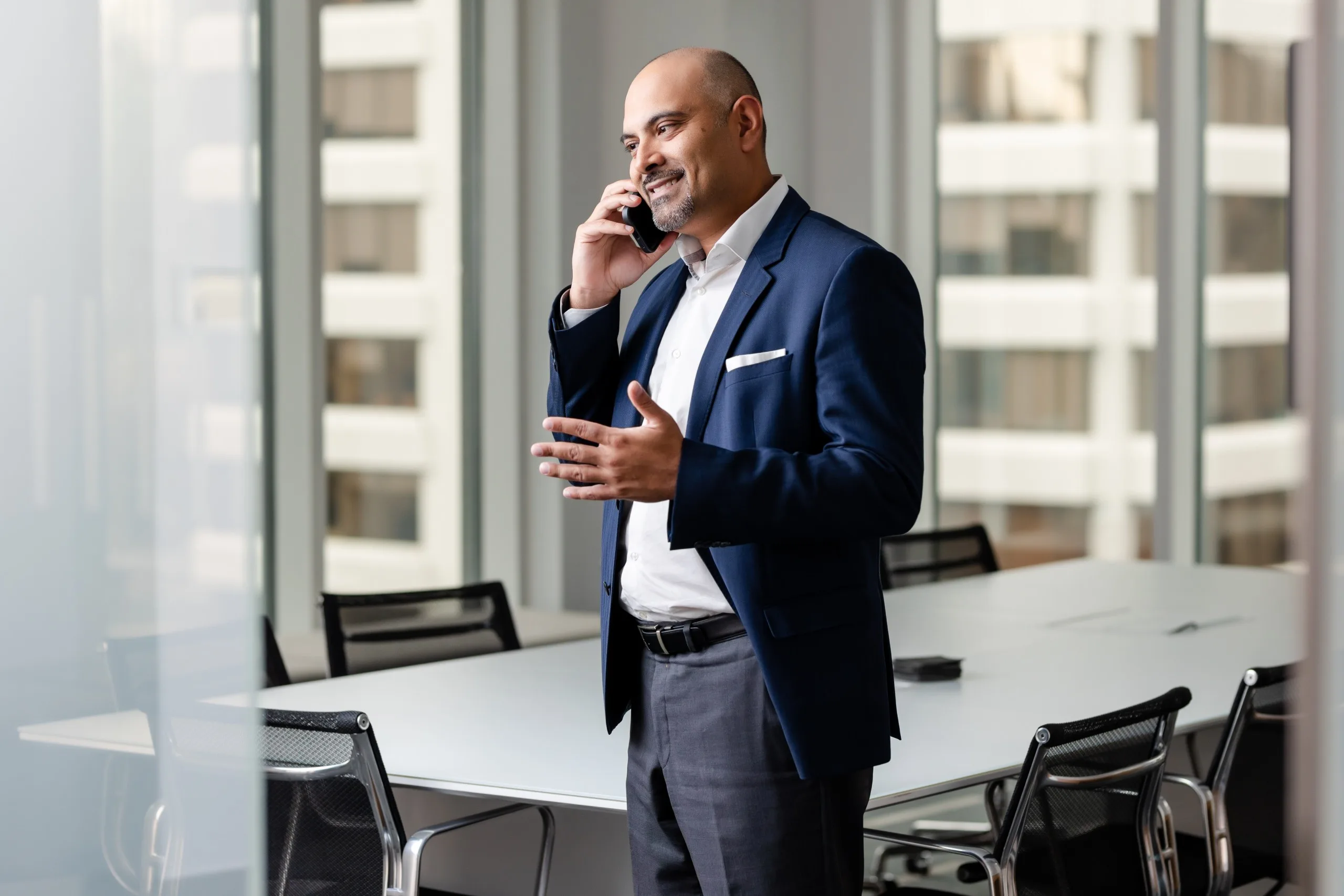 A man in a suit talking on the phone in an office.