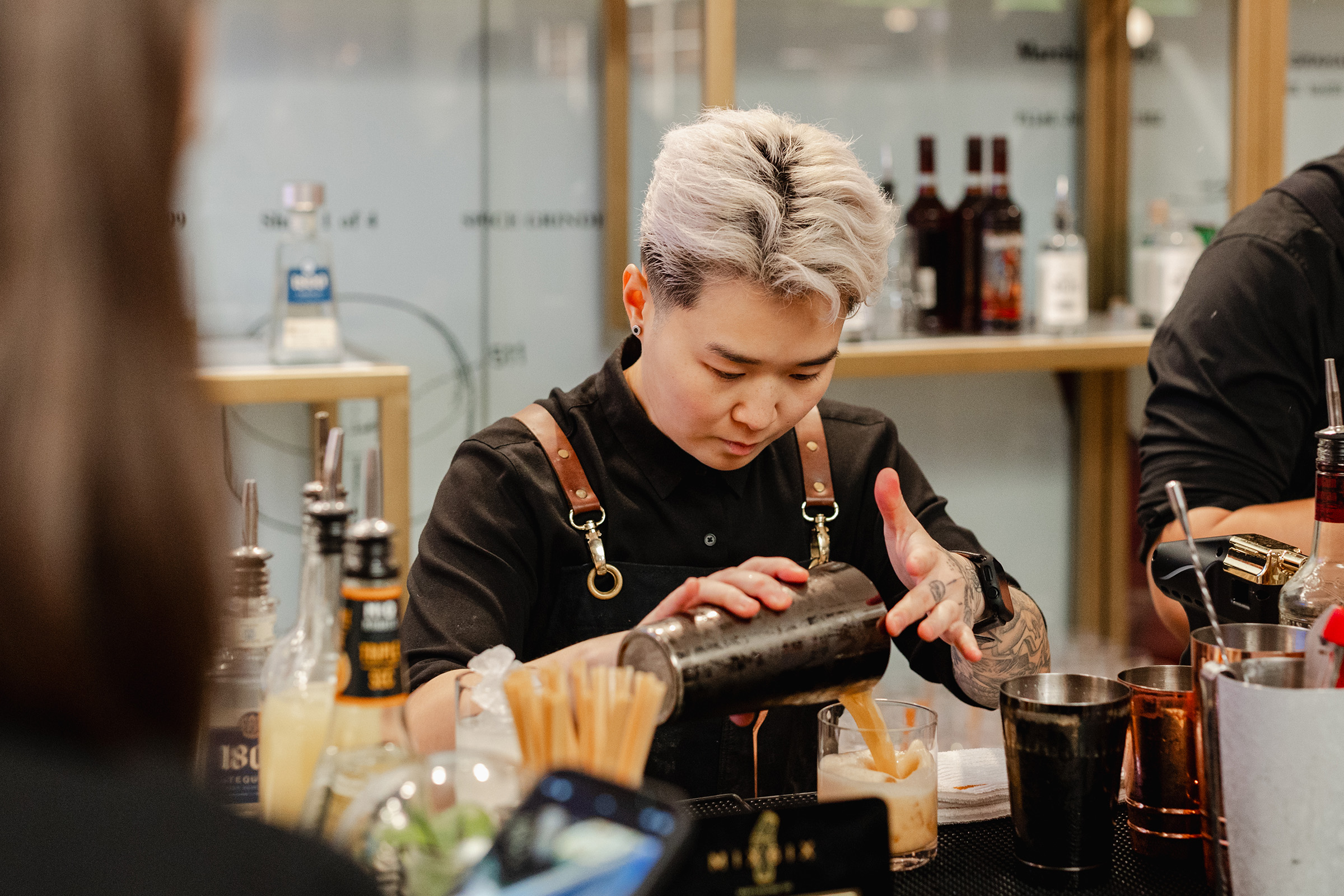 A bartender expertly pouring a drink into a glass, showcasing their exceptional content creation skills.
