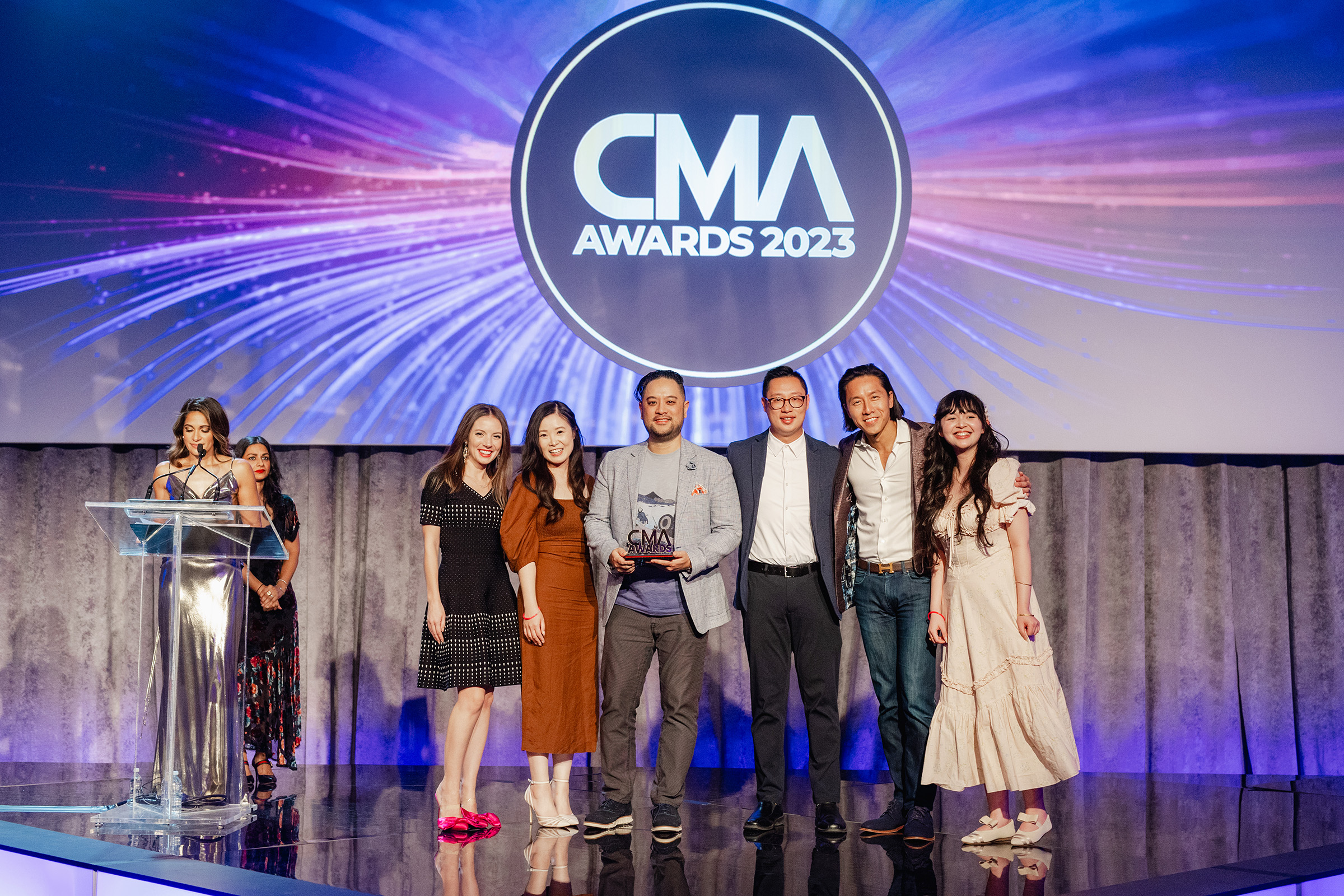 A group of people standing on stage at the CMA Awards for content creation.