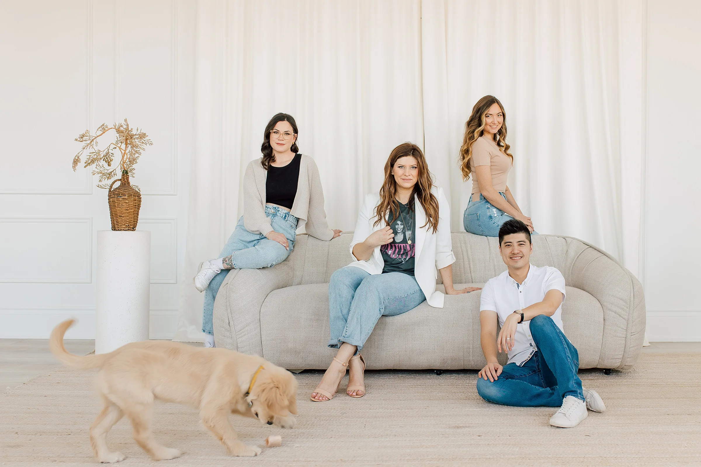 Four people sitting on a couch with a dog.