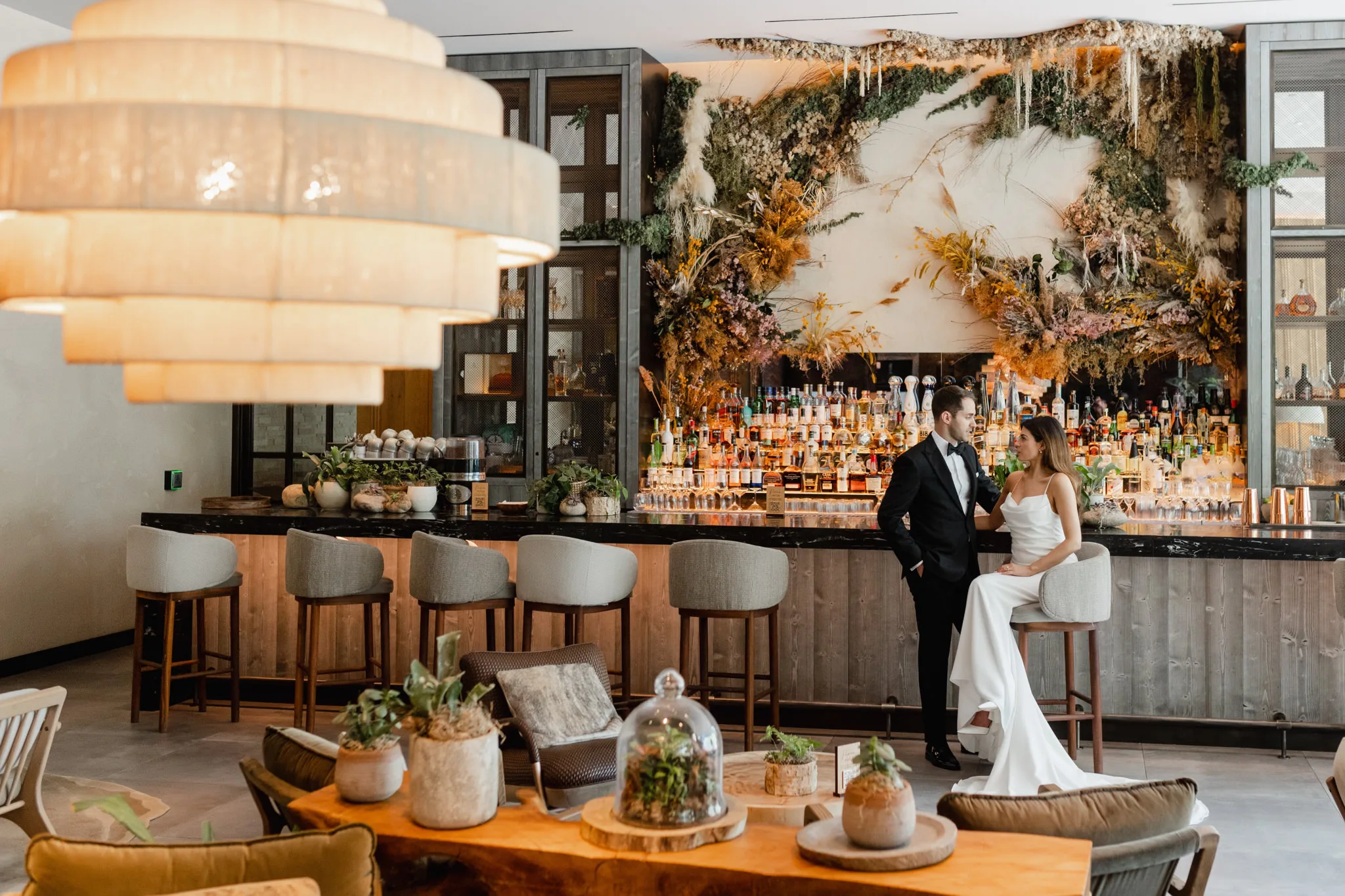 A bride and groom standing in front of a bar.