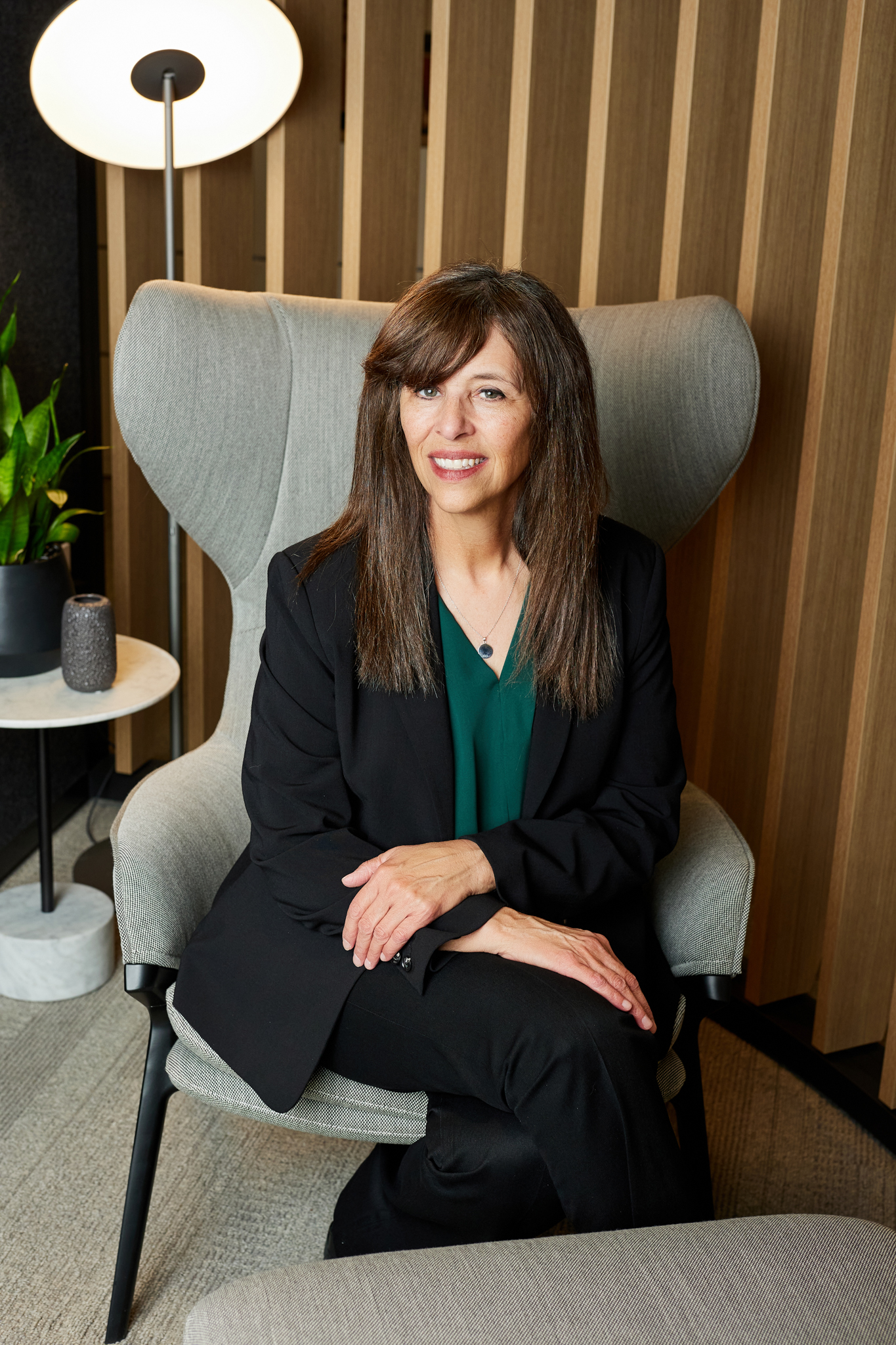 A woman in a business suit sitting on a chair captured in event photography.
