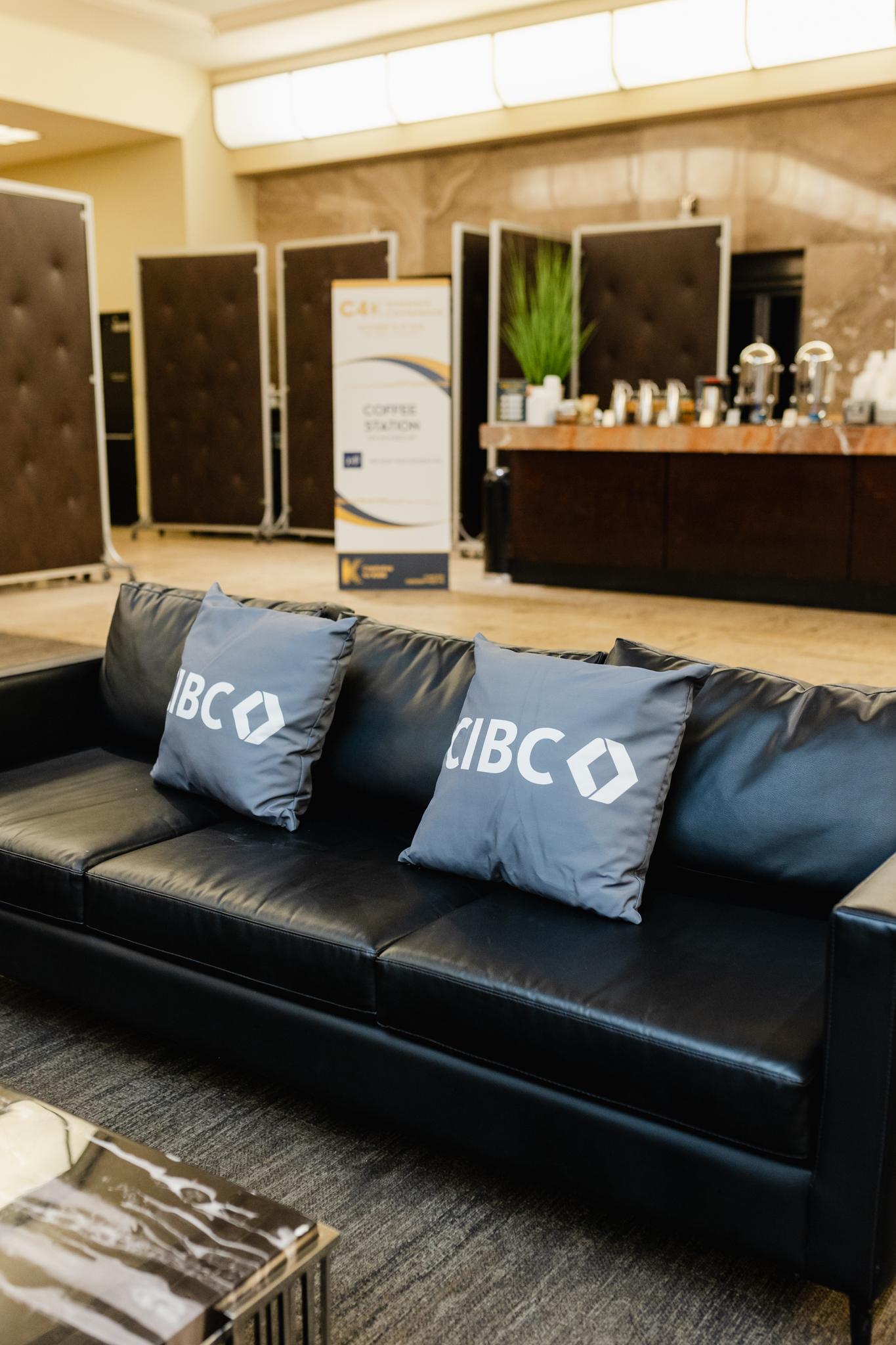A black couch with pillows in a conference lobby.