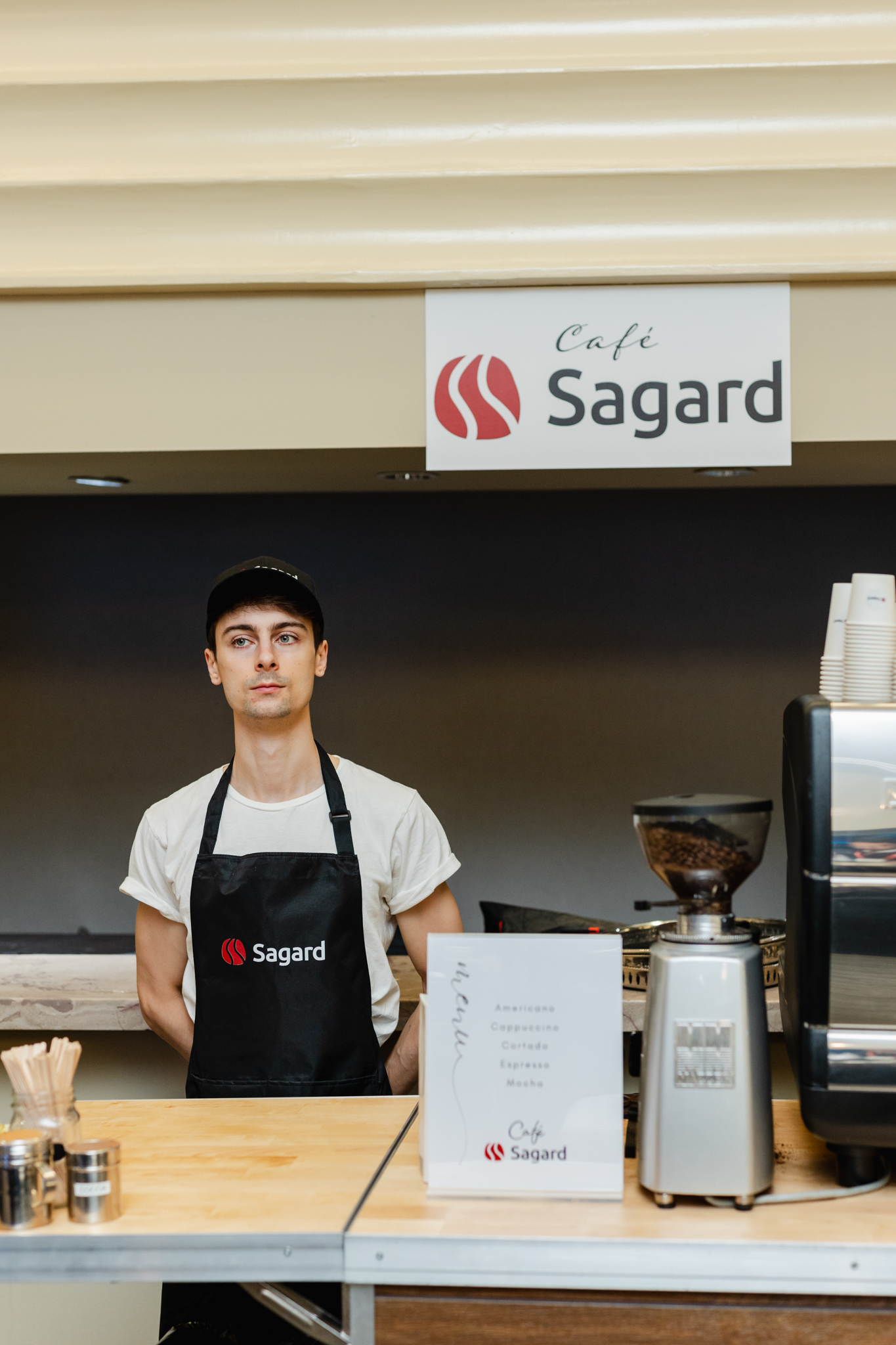 Conference Photography: A man standing in front of a coffee shop with a sign that says sagard, captured through conference photography.