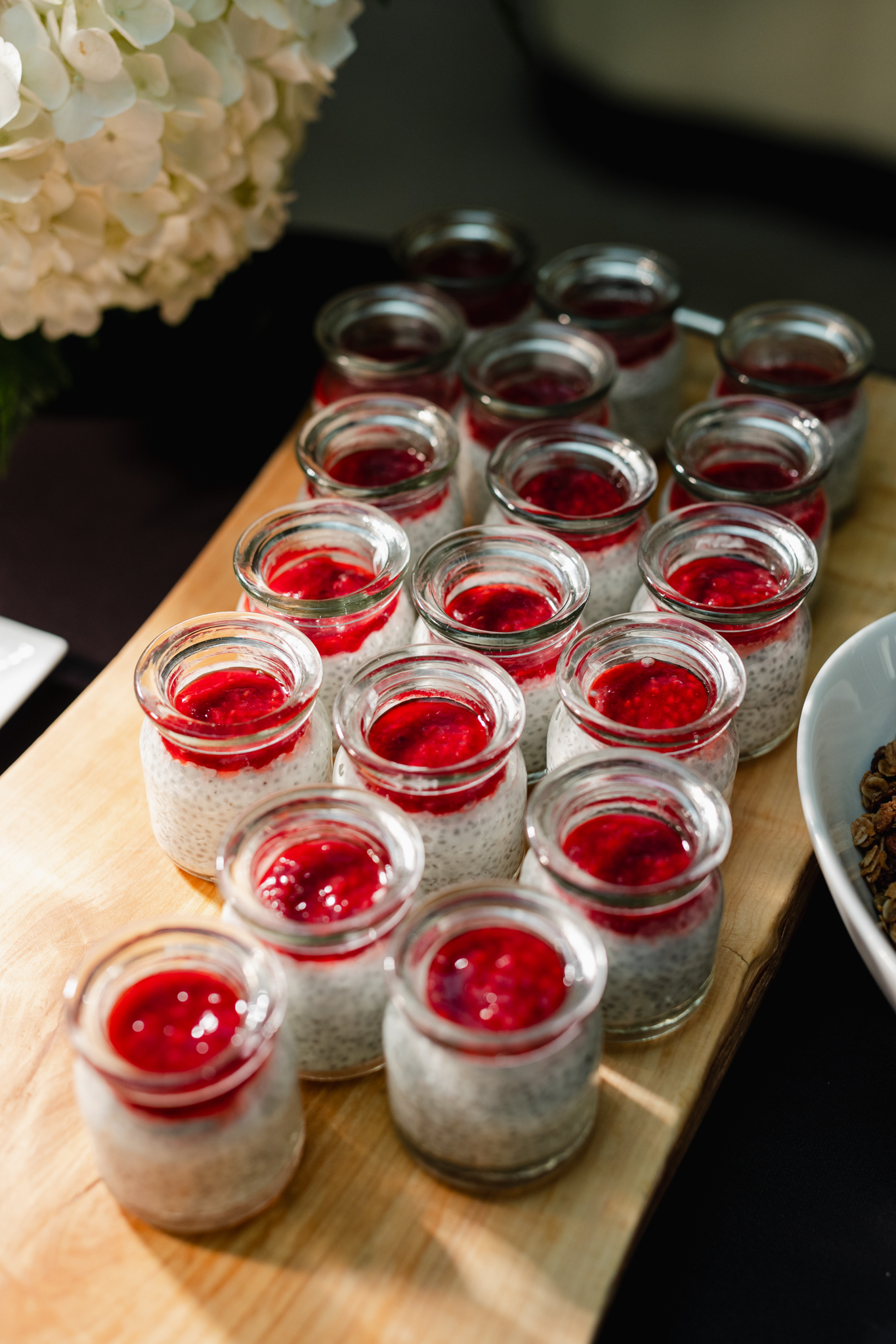 Small jars of raspberry sorbet displayed on a wooden cutting board for a conference photography session.