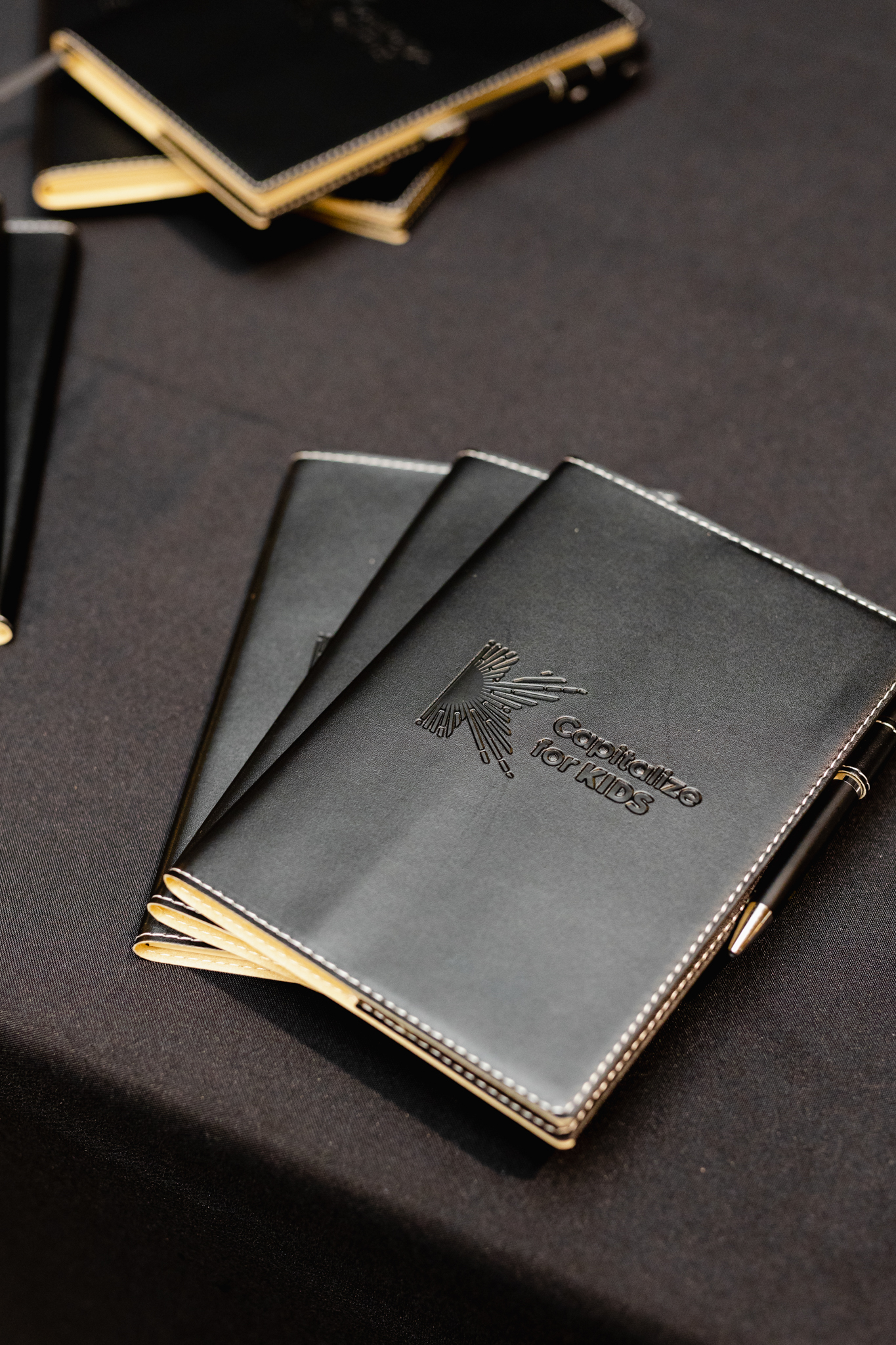Conference attendees will find a striking display of black and gold notebooks elegantly arranged on a table.
