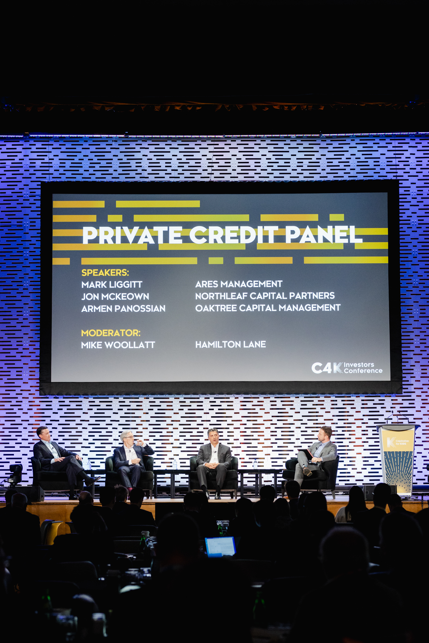 Conference participants on stage at a private credit panel.