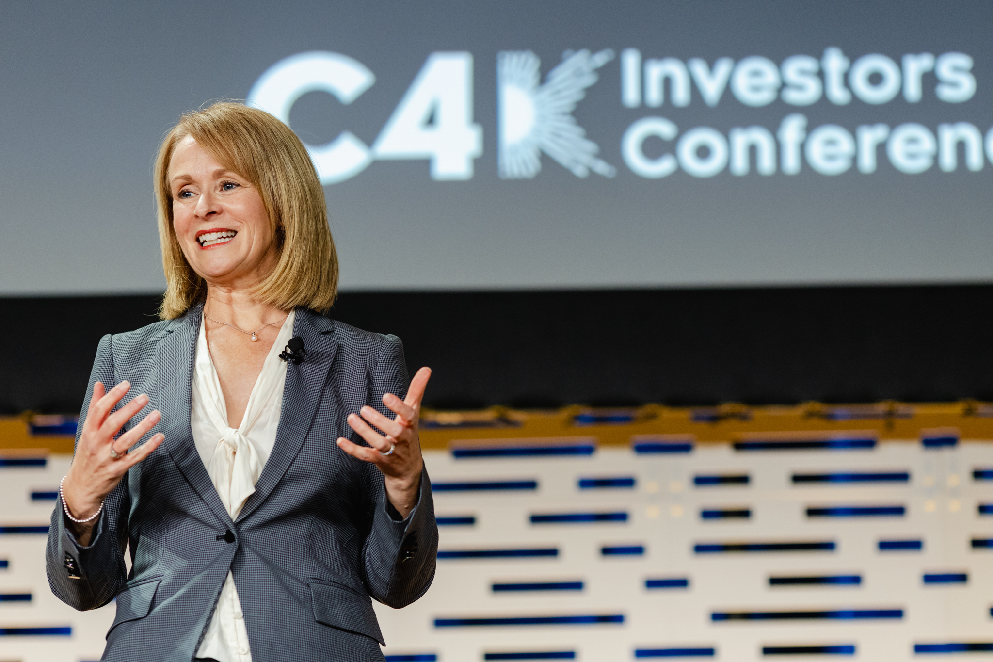 A woman standing in front of a screen at the c4 investors conference.