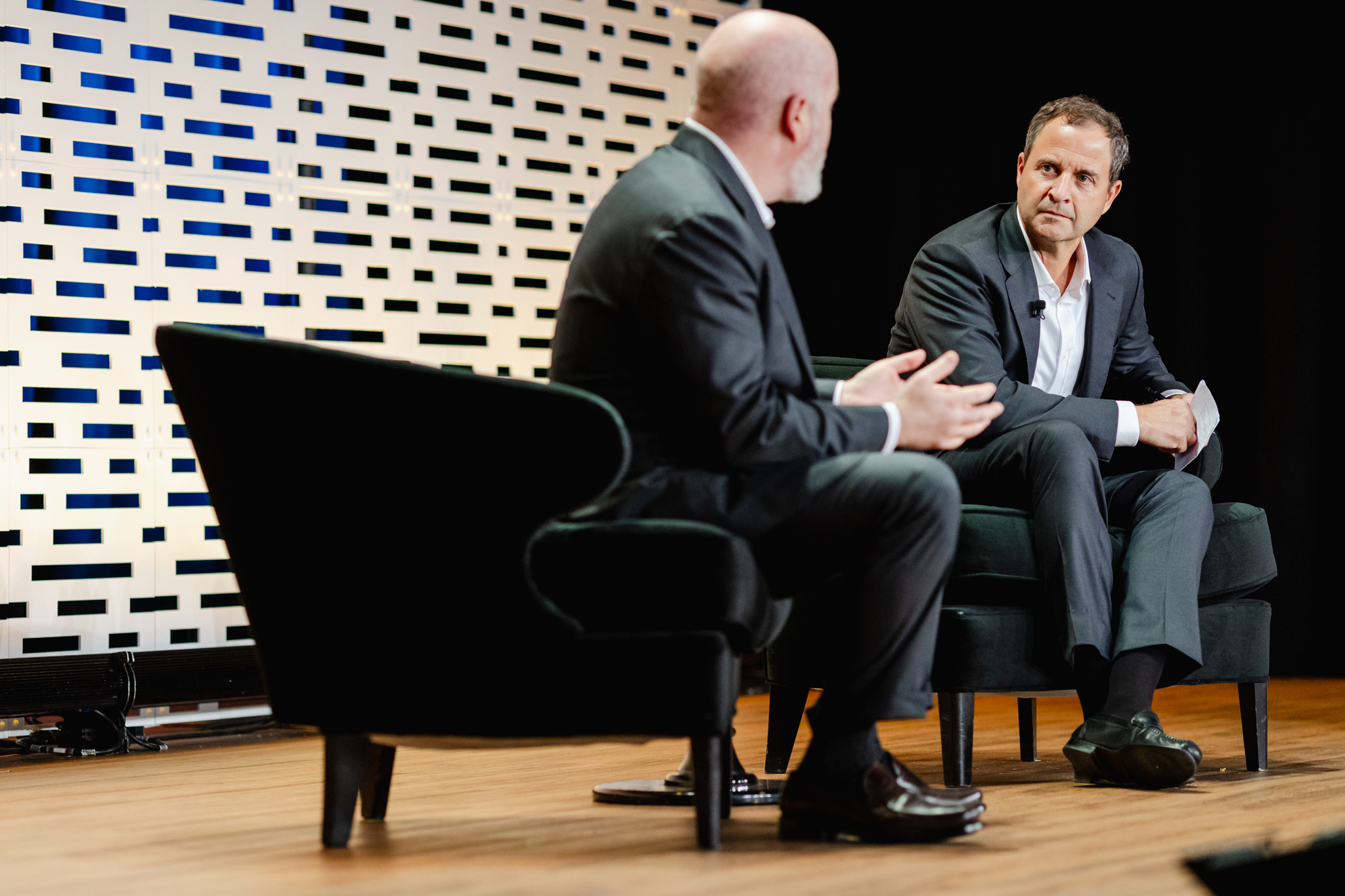 Two men engaged in a conversation on stage during a conference.