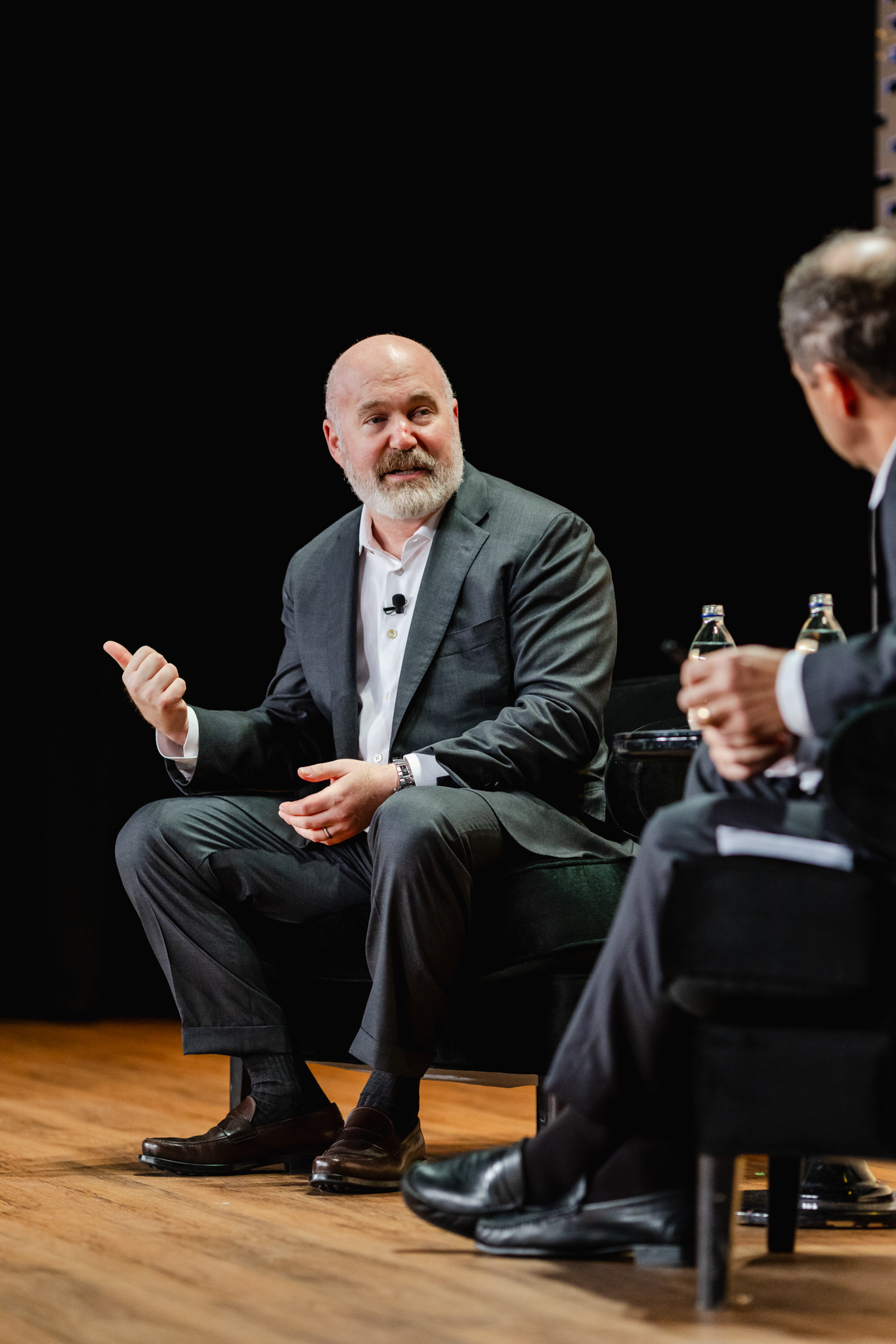 Two men engaged in a conference conversation on stage.