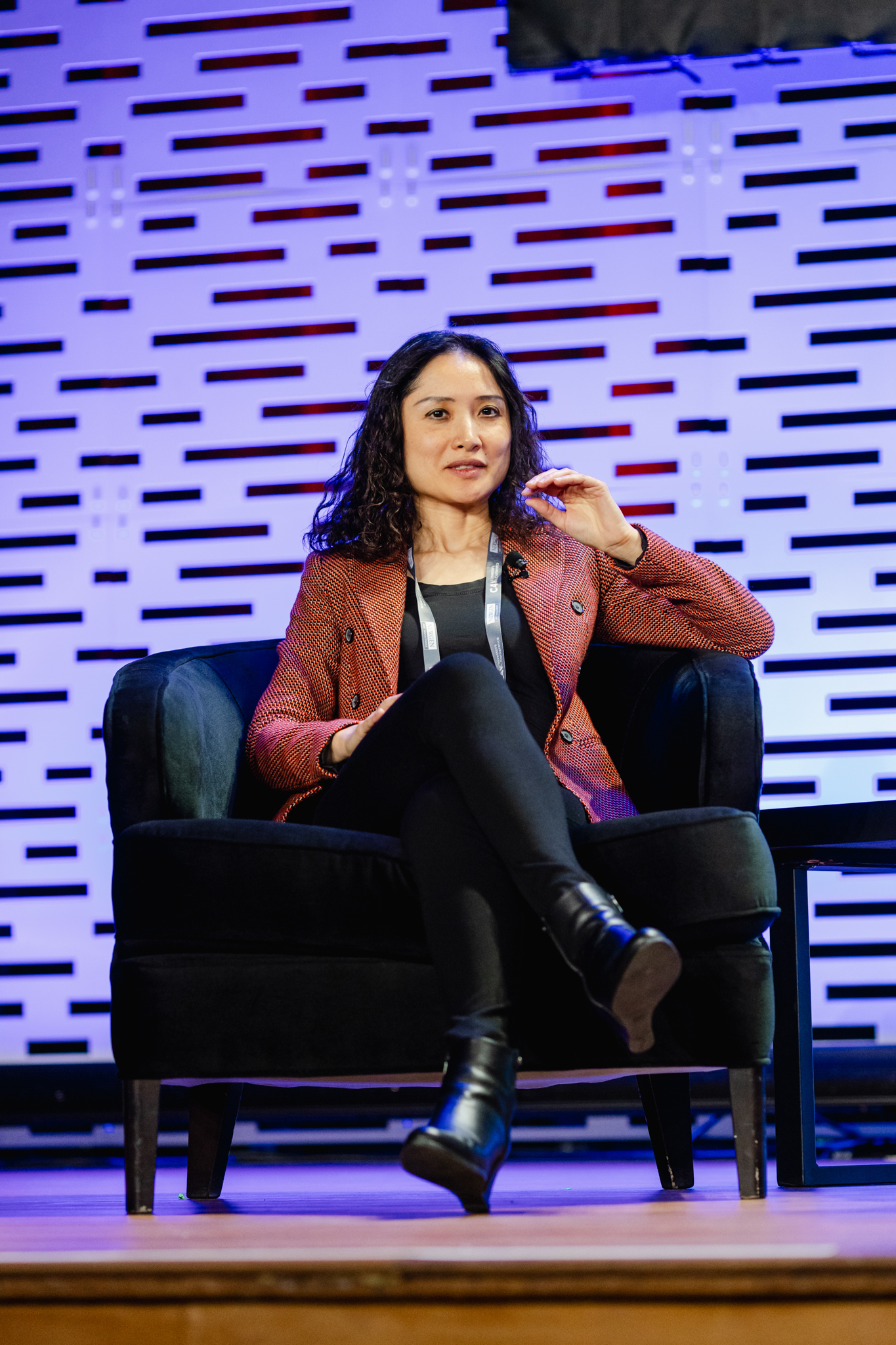 A woman sitting in a chair on stage at a conference.