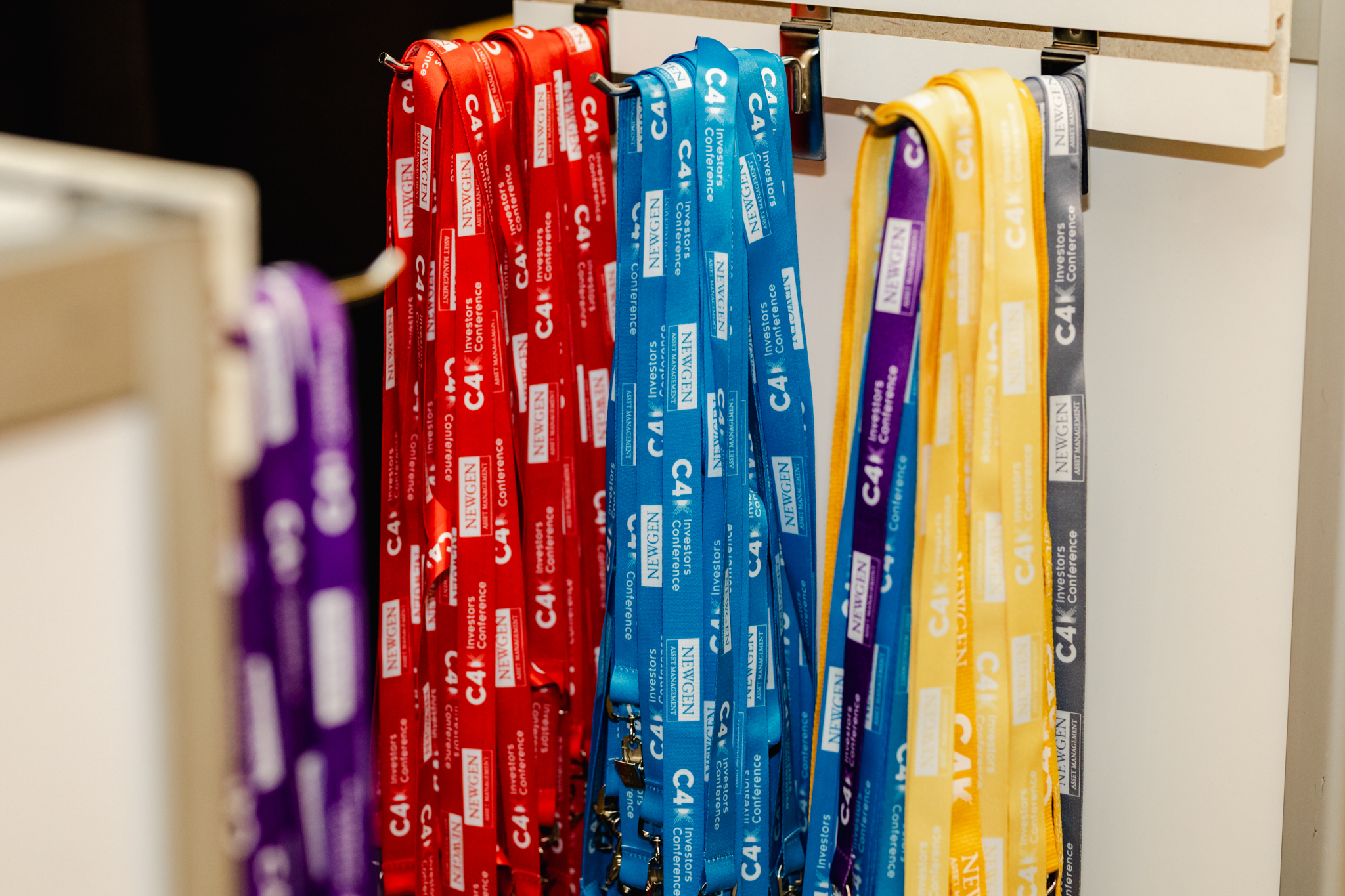 A group of conference lanyards hanging on a rack.