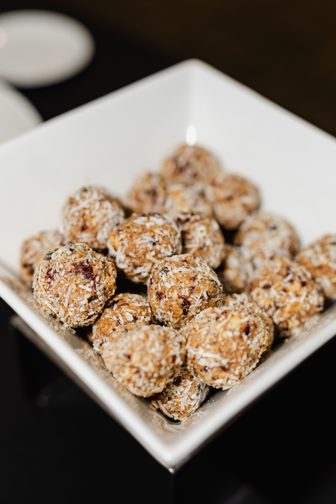 A white bowl filled with nut balls on a conference table.