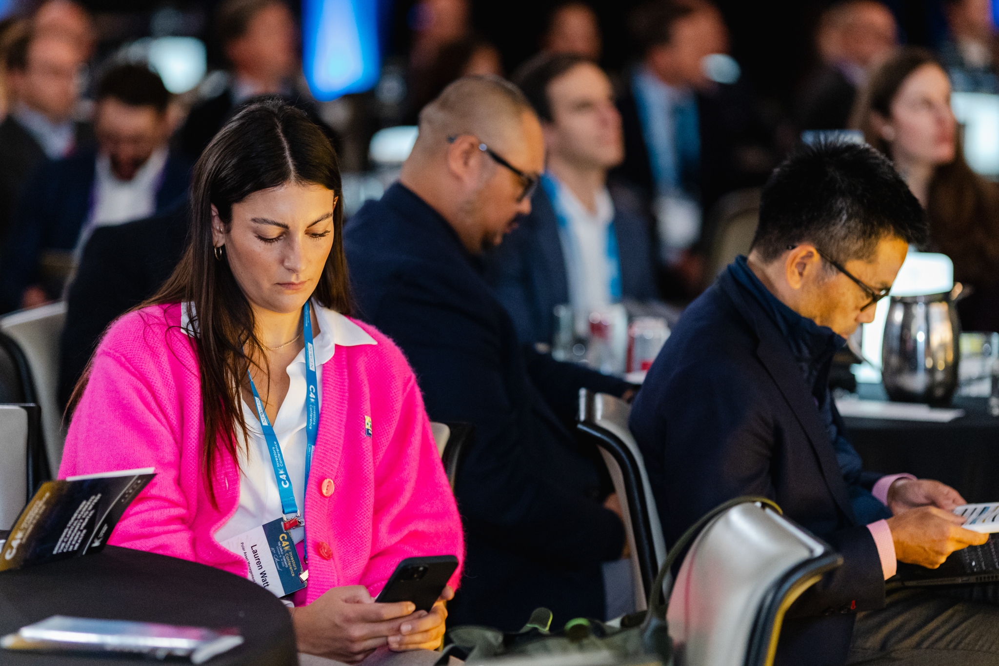 A group of people at a conference engrossed in their phones.