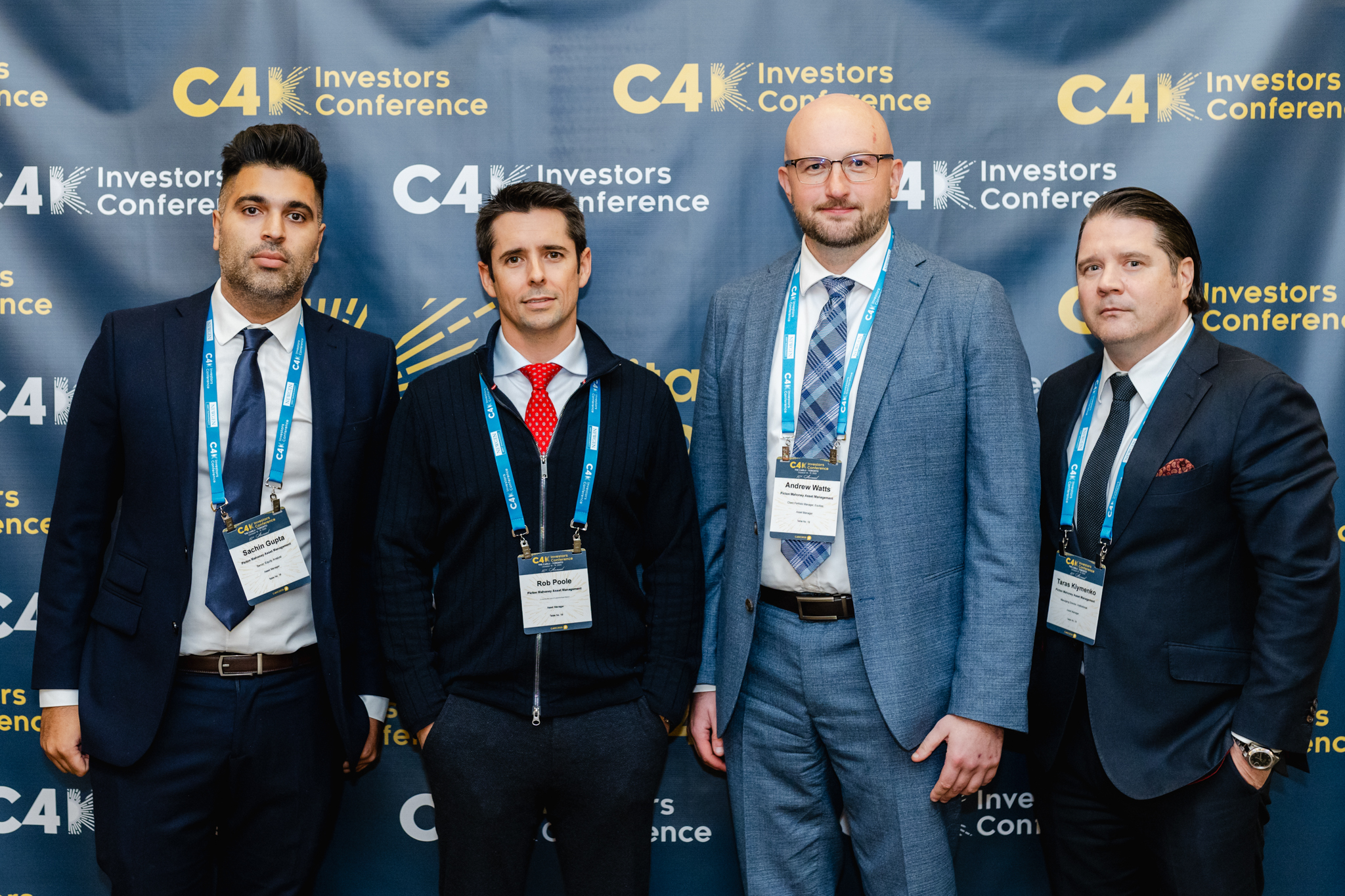 Four men in suits posing for a photo at the conference.