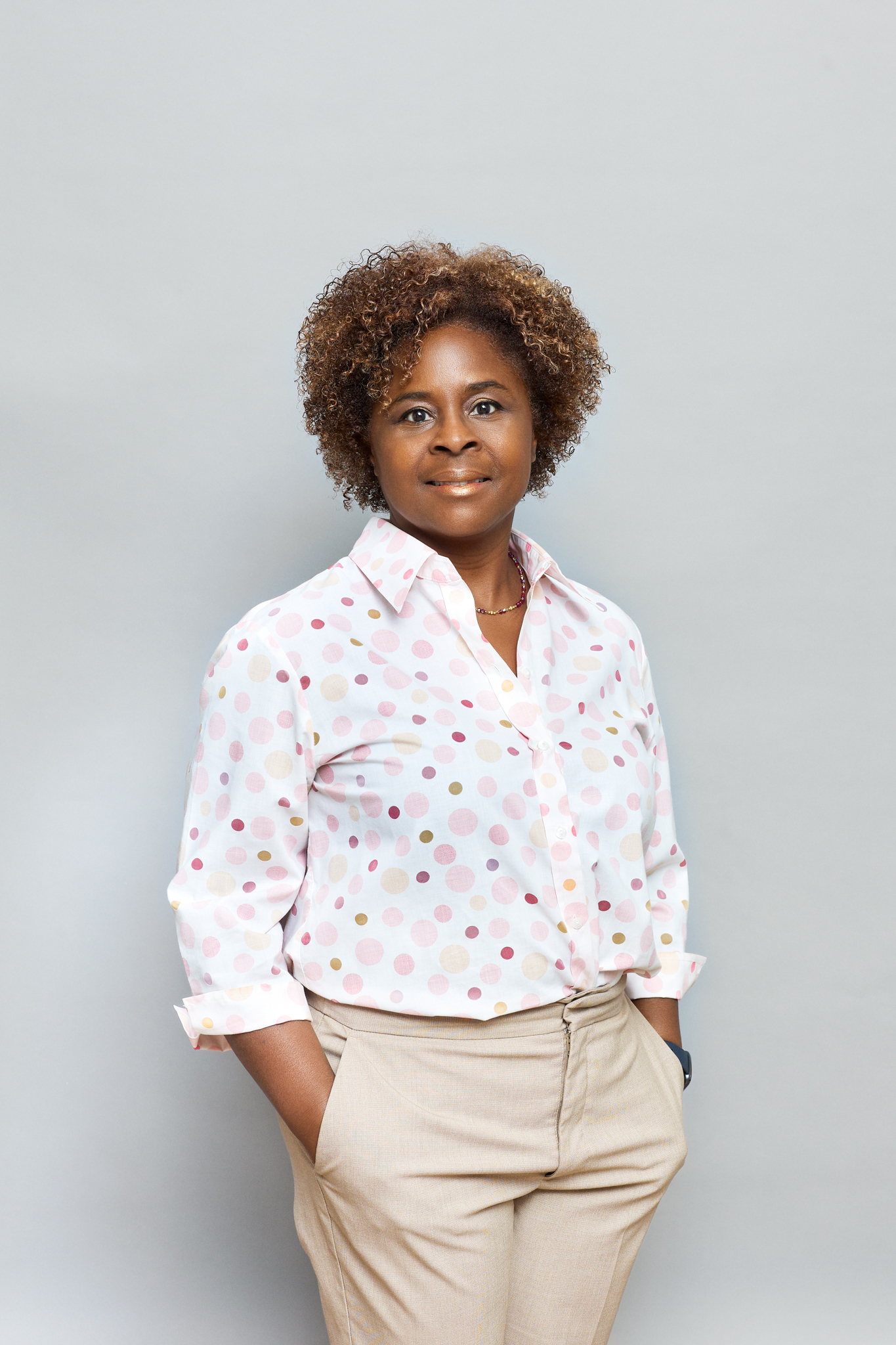 A black woman in a polka dot shirt and tan pants captured through event photography.