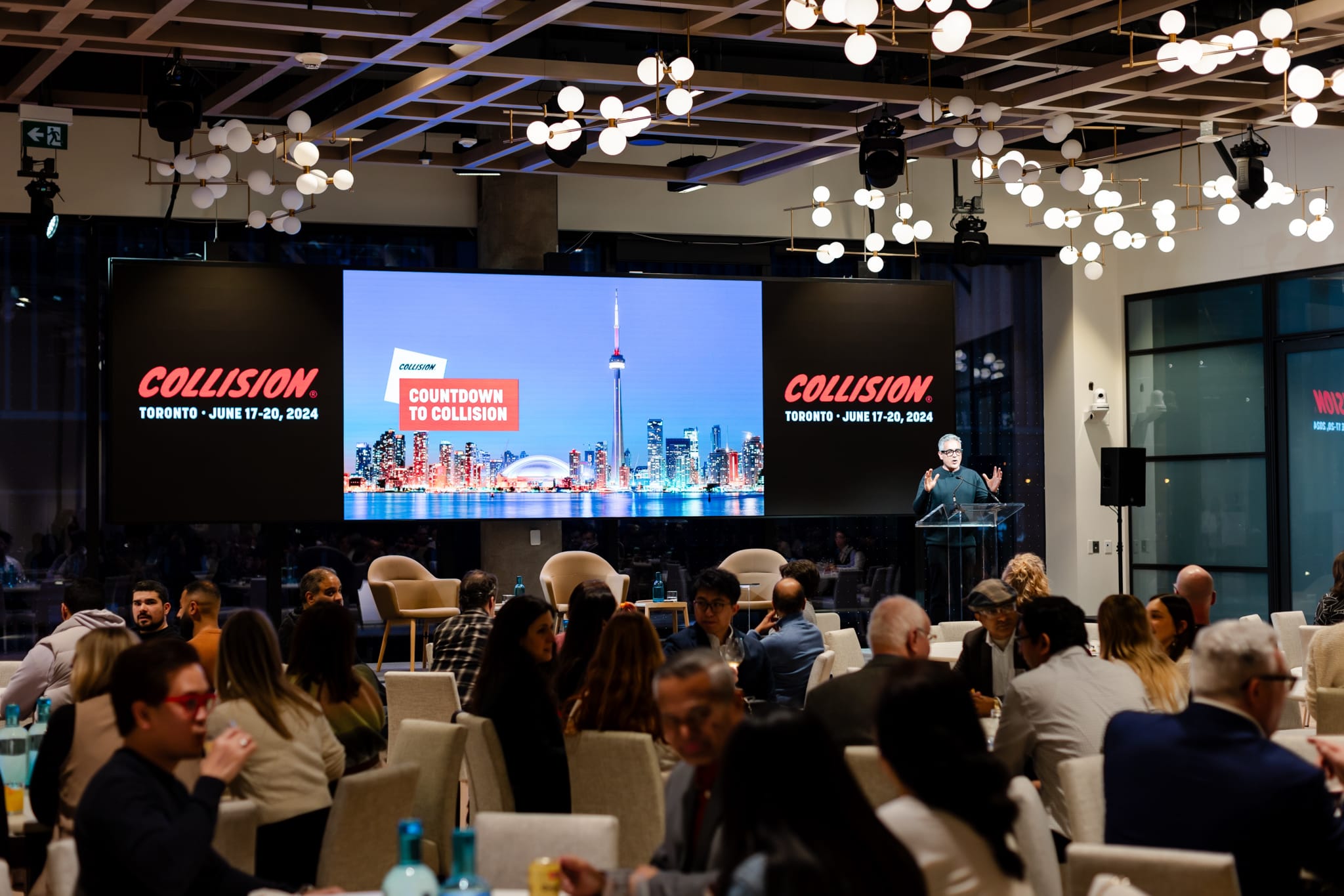 Event photography captures a group of people sitting at tables in a large room.
