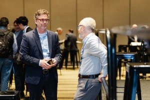 Two men having a conversation at a conference event, captured in event photography.