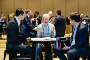 Three professionals engaged in a discussion at a conference table during an event photography session.