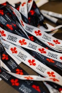 A pile of invest in Canada lanyards with maple leaf motifs, captured in event photography.