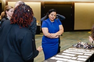 A woman in a blue dress stands behind a table with name tags, observing attendees at an event photography networking event.