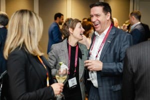 Three professionals engaging in a cheerful conversation at an event photography networking event, with two of them sharing a laugh.
