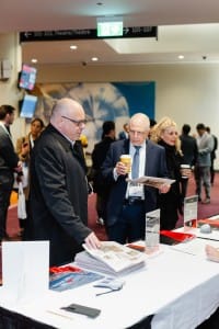 Two men browsing literature at an event photography conference stand.