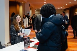 Woman assisting attendees at an event registration desk and coordinating event photography.