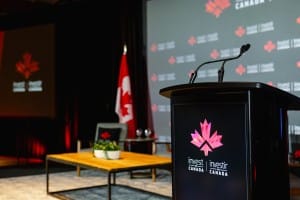Podium at a conference room with "Invest in Canada" branding, Canadian flags in the background, captured during an event photography session.