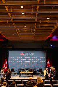 Audience gathering in a conference room with a stage set for a panel discussion at an "Invest in Canada" event, highlighted by event photography.