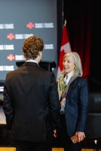 Two professionals having a conversation at an event with sponsorship logos in the background, captured in stunning event photography.