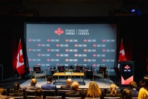 Event photography at a panel discussion setup at an Invest Canada conference with an audience in attendance.