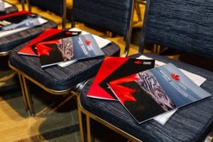 Event photography brochures laid out on seats in an auditorium.
