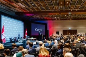 Speaker addressing an audience at a conference branded "Canada," captured through event photography.