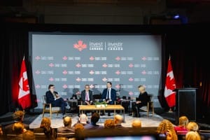 Panel discussion at an invest in Canada event with audience and Canadian flags captured through event photography.