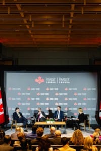 Panel discussion at the Invest Canada event with speakers seated onstage before an audience, captured by event photography.