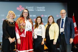 Group of five individuals posing for an event photography shot at an 'invest in Canada' event.