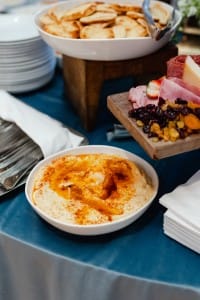 A buffet table adorned with hummus, crackers, and bread captured in event photography.