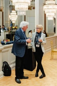 Two people talking in a room with chandeliers, captured during event photography.