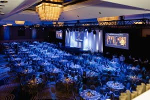 A large ballroom with blue lights and tables set for event photography.