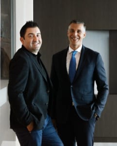 Two men in business attire stand side by side, smiling in a contemporary office setting, capturing the essence of lifestyle portraits.