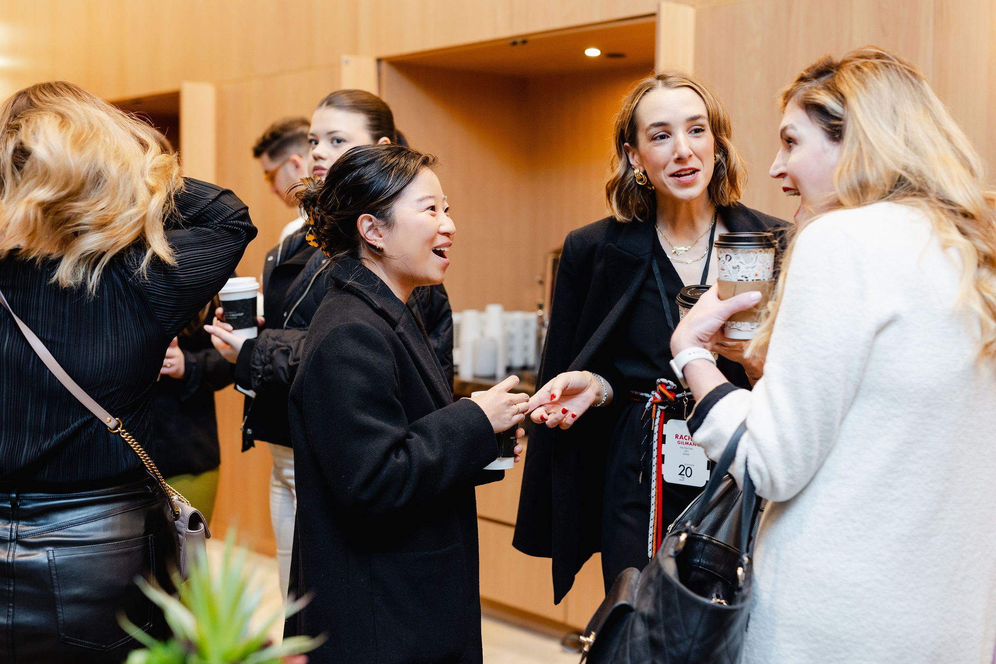A group of people engages in lively conversation, drinks in hand, captured through the lens of brand photography in an inviting indoor setting.