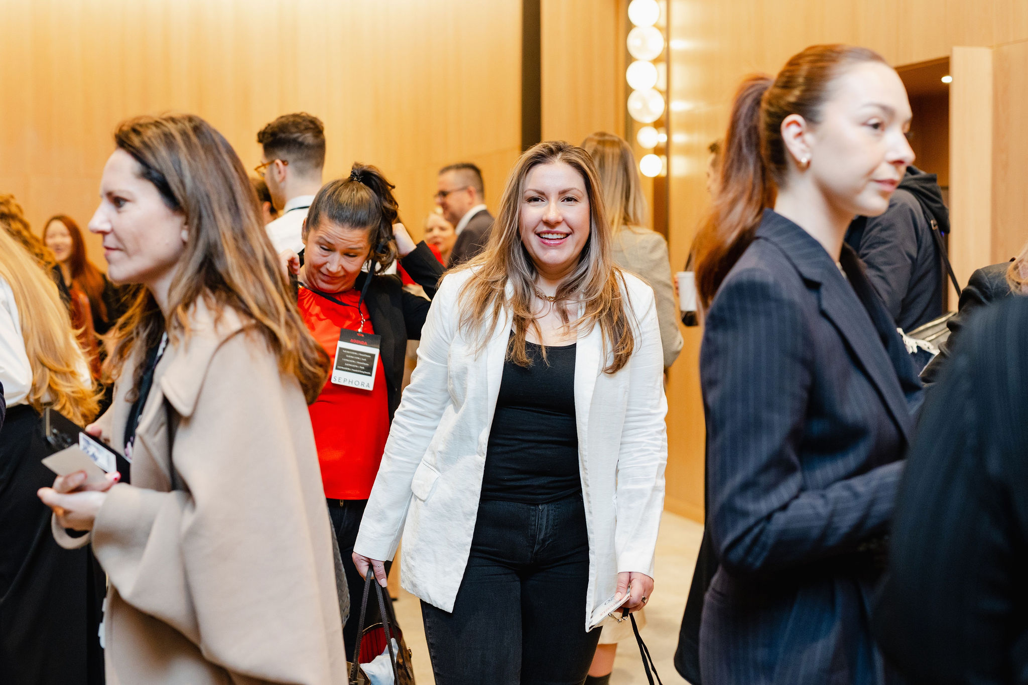 A group of professionals in business attire walk and converse, embodying brand photography, in a well-lit room with wood-paneled walls.