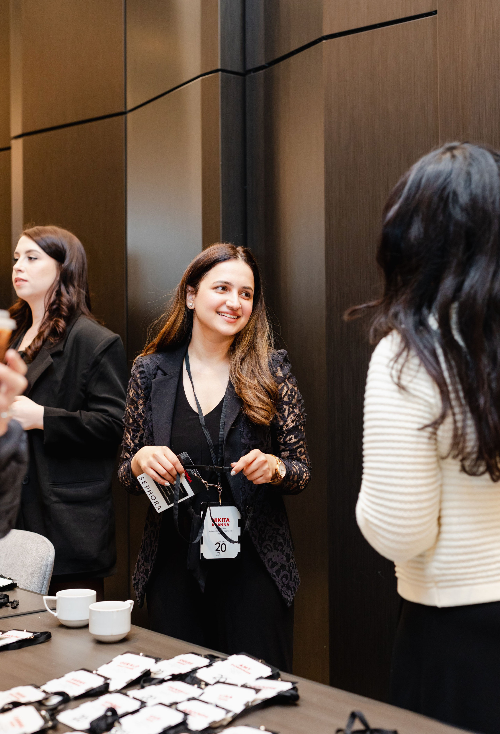 The woman is smiling and engaging in conversation at a table adorned with name tags and two cups, perfectly capturing the essence of brand photography.
